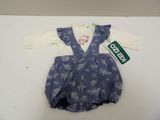 une combinaison pour bébé, avec une chemise blanche et une salopette bleue, posée sur une table