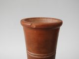 a brown vase sitting on top of a white table
