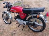 une moto rouge garée dans une cour, près d'un arbre