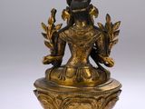 a gold statue of a woman holding a flower on top of a bowl
