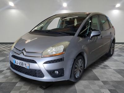 La petite voiture argentée est garée dans le garage, sur le sol à damier.