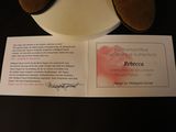 a teddy bear sitting on top of a plate next to a certificate
