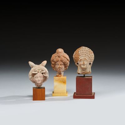 un ensemble de quatre sculptures représentant des têtes, montées sur des socles en bois