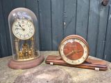 deux horloges posées sur une table recouverte d'une cloche en verre