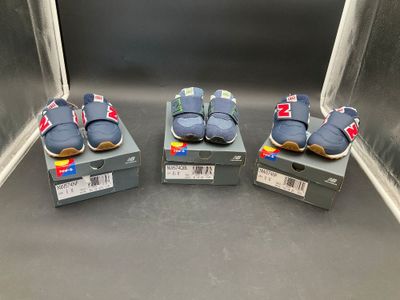 three pairs of baby shoes sitting on top of boxes