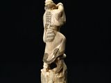 an antique carved ivory figurine of a monkey on a tree stump