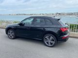 Le SUV Audi noir est garé sur le bord de la route, près de l'eau.