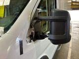 a white van parked in a garage with a mirror on the side of the van