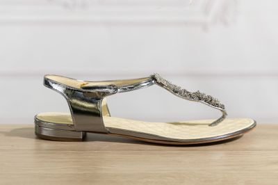 un gros plan sur une paire de sandales argentées posées sur une table en bois