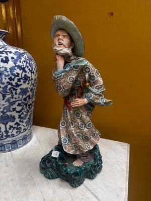 a figurine of a man with a hat on a table next to a vase