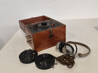 une boîte en bois sur laquelle sont posés un casque audio et une paire d'écouteurs