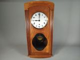 une horloge en bois avec un cadran noir sur fond blanc