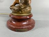 bronze statue of a woman sitting on a rock with a bird on her shoulder