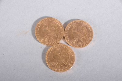 three gold coins sitting on top of each other on a white surface