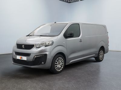 La camionnette argentée est garée dans une pièce blanche au sol noir.