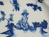 a blue and white plate with a picture of a woman and a bird on it