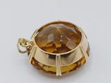 a close up of a gold colored pendant with a faceted brown stone
