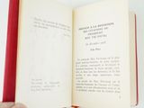 someone is holding an open book in their hand on a white surface
