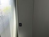 a metal cabinet in the corner of a room with blinds