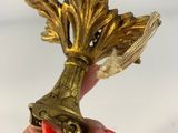 someone is holding a golden vase with a flower on it