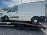 une camionnette blanche sur une remorque à plateau dans un parking