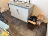 une petite armoire dans un coin de la pièce, sur laquelle est posé un ordinateur portable