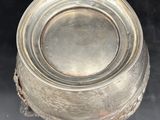 an antique silverplated bowl on a black surface with a black background