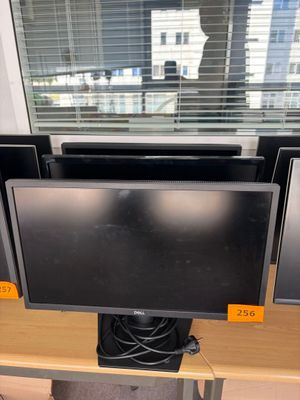 trois écrans d'ordinateur posés sur un bureau devant une fenêtre