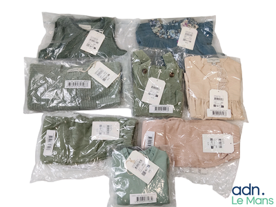 de nombreux t-shirts de différentes couleurs, rangés dans des sacs posés sur une surface blanche