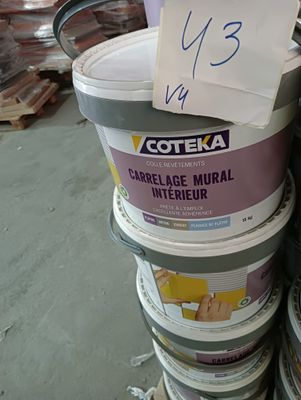 plusieurs seaux de peinture empilés les uns sur les autres dans un entrepôt