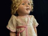 a small doll with blonde hair and a pink dress