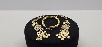 une paire de boucles d'oreilles en or et une bague dans un écrin noir