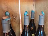 several bottles of wine are lined up on a wooden shelf