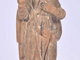 une vieille statue représentant un homme coiffé d'un chapeau et vêtu d'une robe