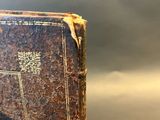 an old book sitting on top of a table next to a glass
