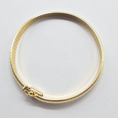 a close up of a gold bracelet on a white surface