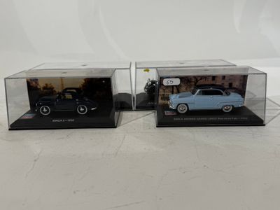 a pair of diecast cars in display cases on a white surface