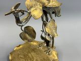 bronze figurine of a bird on a branch with flowers
