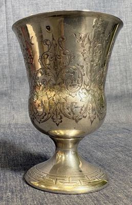 un vase en argent posé sur une table, sur fond gris