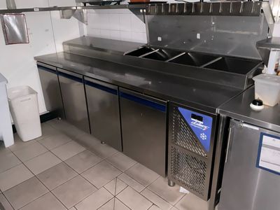 une cuisine équipée de plans de travail et d'un évier en inox