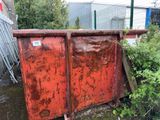 une benne à ordures rouge rouillée posée au milieu d'une cour