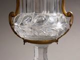 an antique glass vase on a stand with gold trimmings