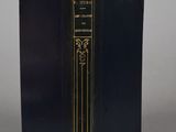 an old black book with gold trim sitting on top of a table