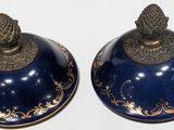 two blue vases with gold designs on them on a white surface