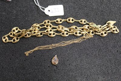 a close up of a gold chain bracelet with a tear charm