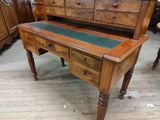 a wooden desk with a green top and drawers