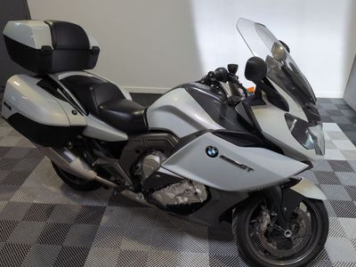 une moto argentée et noire garée sur un sol à damier