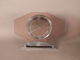 une horloge rose posée sur un socle en métal
