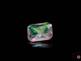 un gros plan d'un diamant vert et rose sur une surface noire