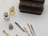 a brown leather case with various tools and a bottle of perfume